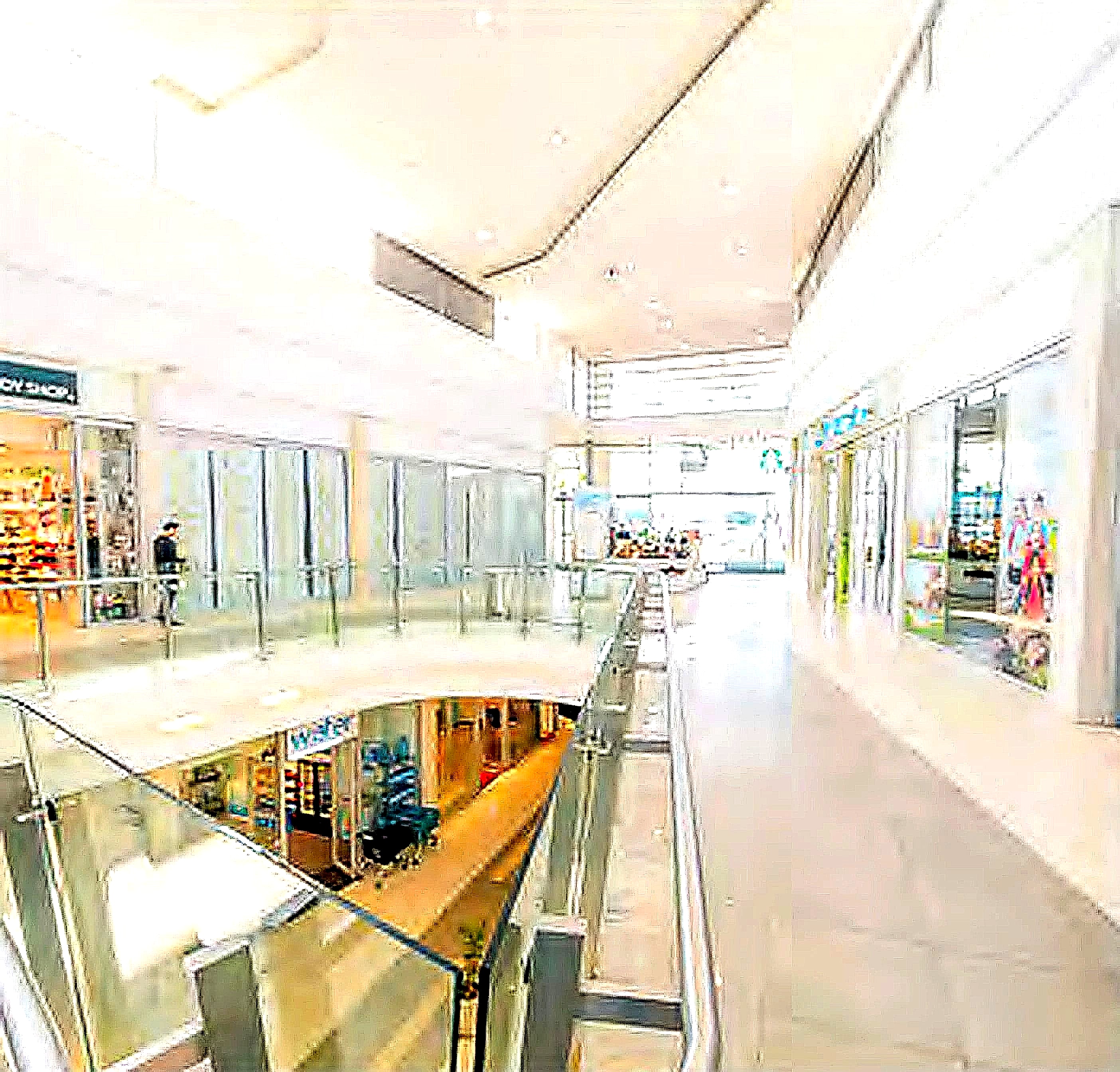 A mall corridor lined with storefronts and glass railings across multiple levels
